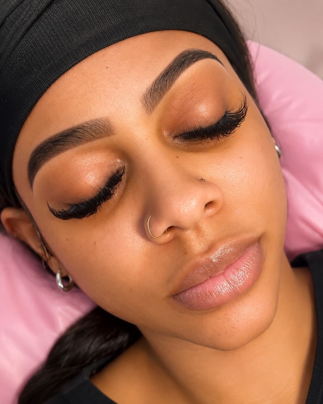 A full volume lash set over laminated brows, resting on the lash pillow